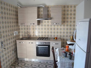 A kitchen with patterned wallpaper, a stove, oven, and a refrigerator.