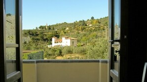 A balcony with a view of a hillside, a chair, and a door. - Organic Farmholiday In The Middle Of Olive Grove 1 (Castelfranco Piandisco)