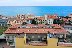 A coastal town with buildings featuring red-tiled roofs and a view of the sea. - Bilocale 30 Metri Dalla Spiaggia (San Vincenzo)