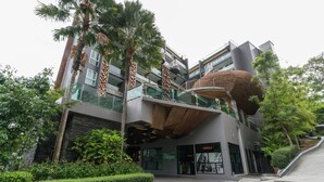 Um edifício moderno com uma estrutura esférica singular, várias varandas e vegetação exuberante.