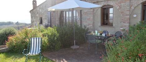A patio with a table and chairs, a striped chair, and a white umbrella.