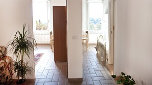 A hallway with a tiled floor, a wooden door, and a view of an outdoor balcony. - Perugia Antica Sunny apartment (Perugia)