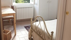 A bedroom with a bed, a wardrobe, a radiator, a window with a view, a table, and a chair. - Perugia Antica Sunny apartment (Perugia)