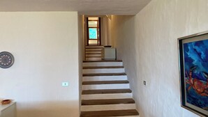 A staircase with white walls and a framed painting on the right. - Domus Olivarum -costa Smeralda Villetta 7 Persone, 4 PK, Wifi, Grande Giardino (Arzachena)