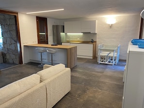 A modern kitchen with a central island, bar stools, and a dining area with a white table and chairs.
