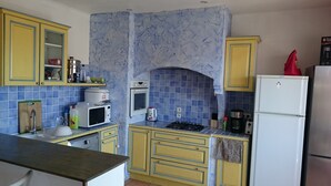 Une cuisine avec des meubles de couleur jaune, un four à micro-ondes, une cuisinière et un réfrigérateur.
