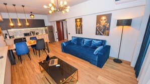 Een moderne woonkamer met een blauwe bank, een salontafel en een eethoek met stoelen en een laptop.