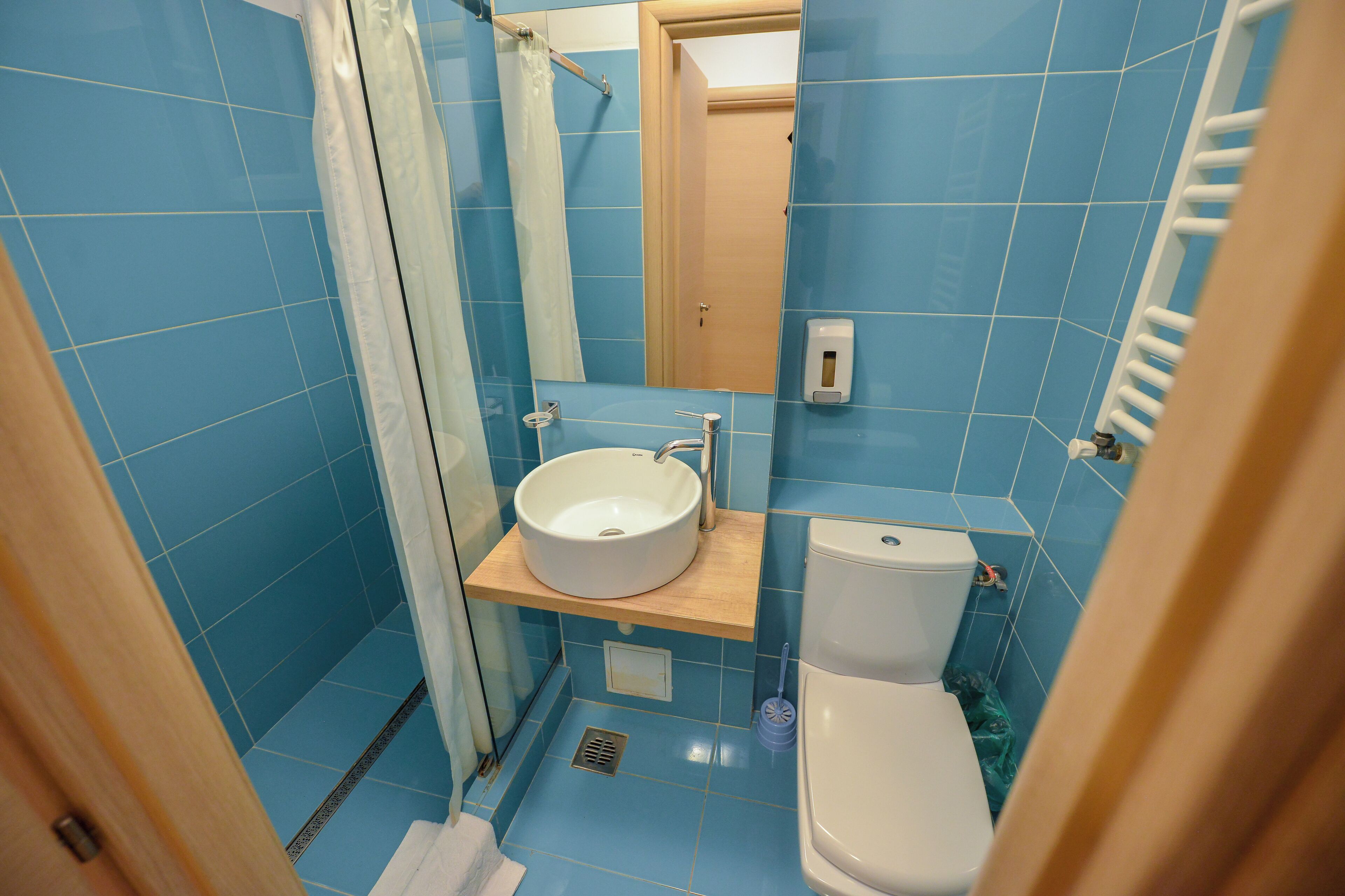 A bathroom with blue tiles, a white sink, a toilet, and a shower curtain.