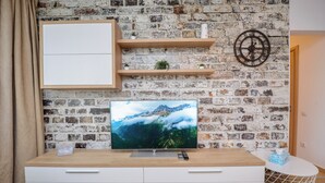 Una sala de estar moderna con pared de ladrillo, mueble bajo para televisor de madera, armarios blancos y una pequeña mesa blanca con una caja de pañuelos.