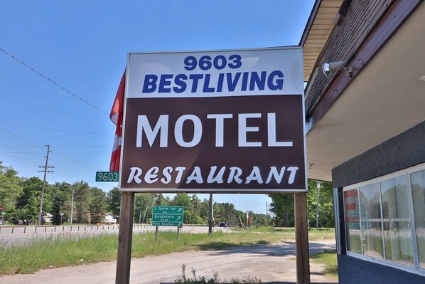 A motel sign with the name '9603 Bestliving' and a green directional sign below it. - BestLiving Motel (Severn)