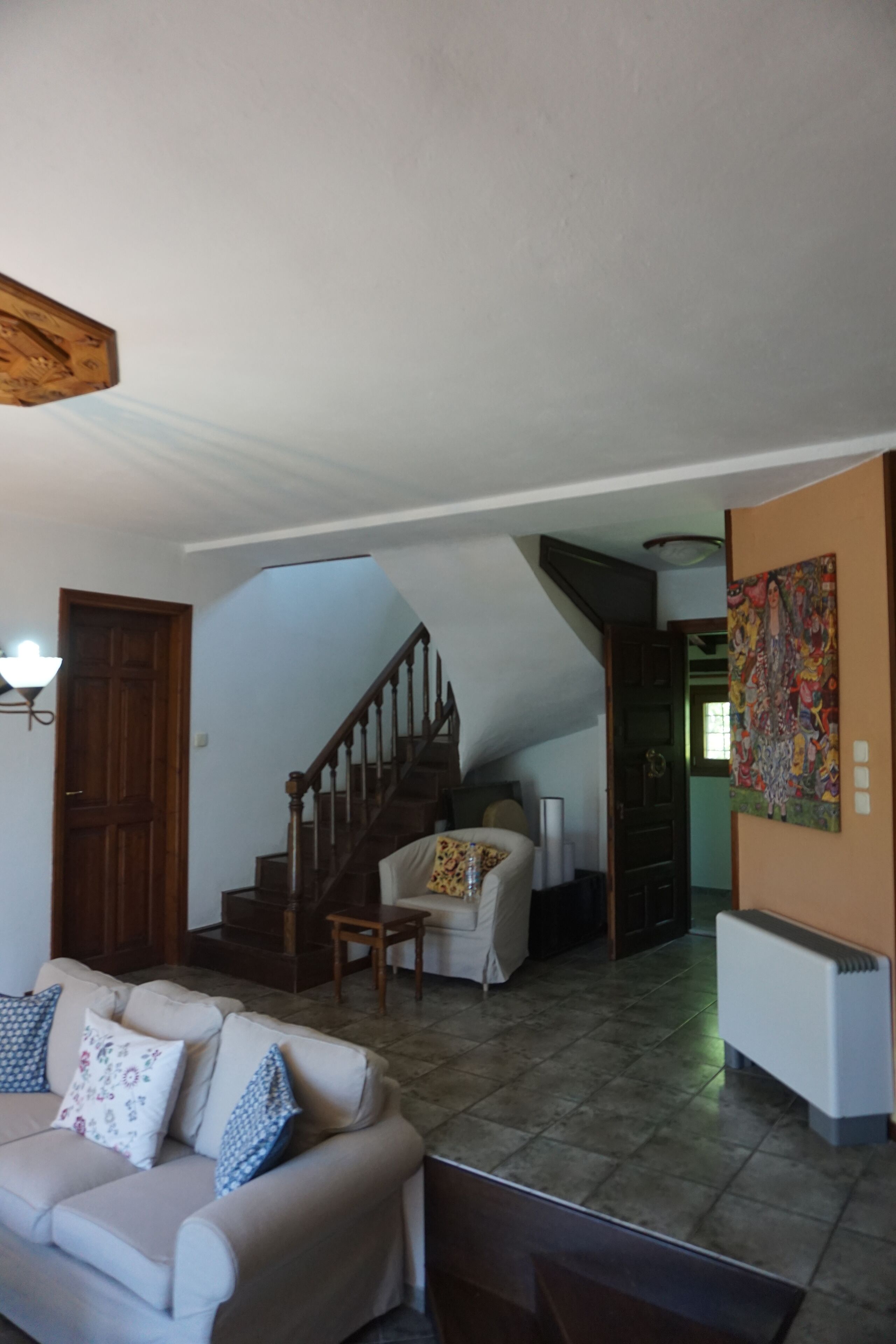 Un salon avec un canapé, un fauteuil, un escalier et un tableau accroché au mur.
