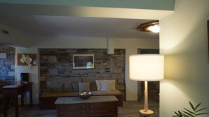 A cozy living room with a stone wall, a sofa, a coffee table, and a lamp.