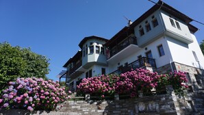 A two-story building with a stone facade, multiple balconies, and a clear blue sky.
