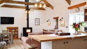 Un salon chaleureux avec une cheminée, un canapé, une table à manger en bois et un coin cuisine.
