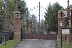 A gated entrance with a wrought iron gate, brick pillars, and a sign indicating the name of the property. - Podere Caldaruccio La Pineta - 26 People Cottage e Villa (Perugia)