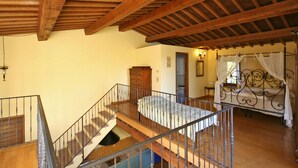 Un dormitorio con techo de madera, cama con dosel y escalera con barandilla.