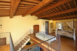 A bedroom with a wooden ceiling, a bed with a canopy, and a staircase with a railing. - Podere Caldaruccio La Pineta - 26 People Cottage e Villa (Perugia)