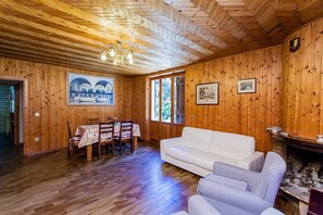 A wooden interior with a dining table, white sofa, and striped chairs. - Podere Caldaruccio La Pineta - 26 People Cottage e Villa (Perugia)