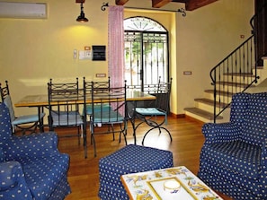 A cozy living room with a dining table, chairs, and a staircase. - Podere Caldaruccio La Pineta - 26 People Cottage e Villa (Perugia)