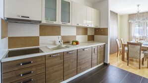 A modern kitchen with a large island, a dining area with a table and chairs, and a chandelier. - TIVAT apartment (NO-9) (Donja Lastva)
