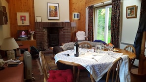 Ein gemütliches Wohnzimmer mit Kamin, einem Esstisch für zwei Personen und einem Fernseher im Hintergrund.