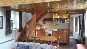 Eine gemütliche Küche mit Holzausstattung, ein Essbereich mit Tisch und Stühlen sowie eine Treppe, die zu einer weiteren Ebene führt.