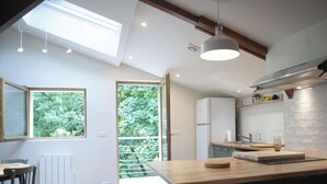 A modern kitchen with a skylight, a dining area, and a view of greenery outside. - Gîte Cosy et Calme, Avec spa et Jardin, au Cœur de Morlaix (Morlaix)