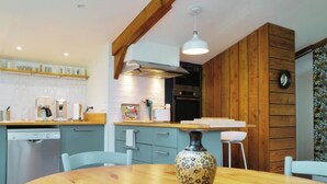 A modern kitchen with wooden accents, a dining table, and chairs. - Gîte Cosy et Calme, Avec spa et Jardin, au Cœur de Morlaix (Morlaix)