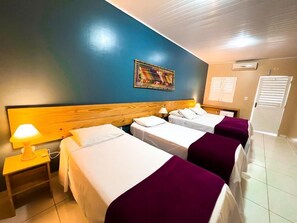 Comfortable accommodations feature a large bed, two smaller beds, and a wall-mounted air conditioning unit.