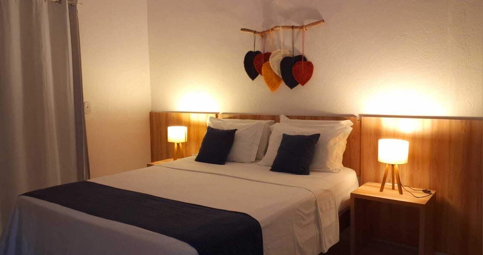 Habitación de hotel con cama, dos lámparas de noche y un adorno de corazones colgantes.