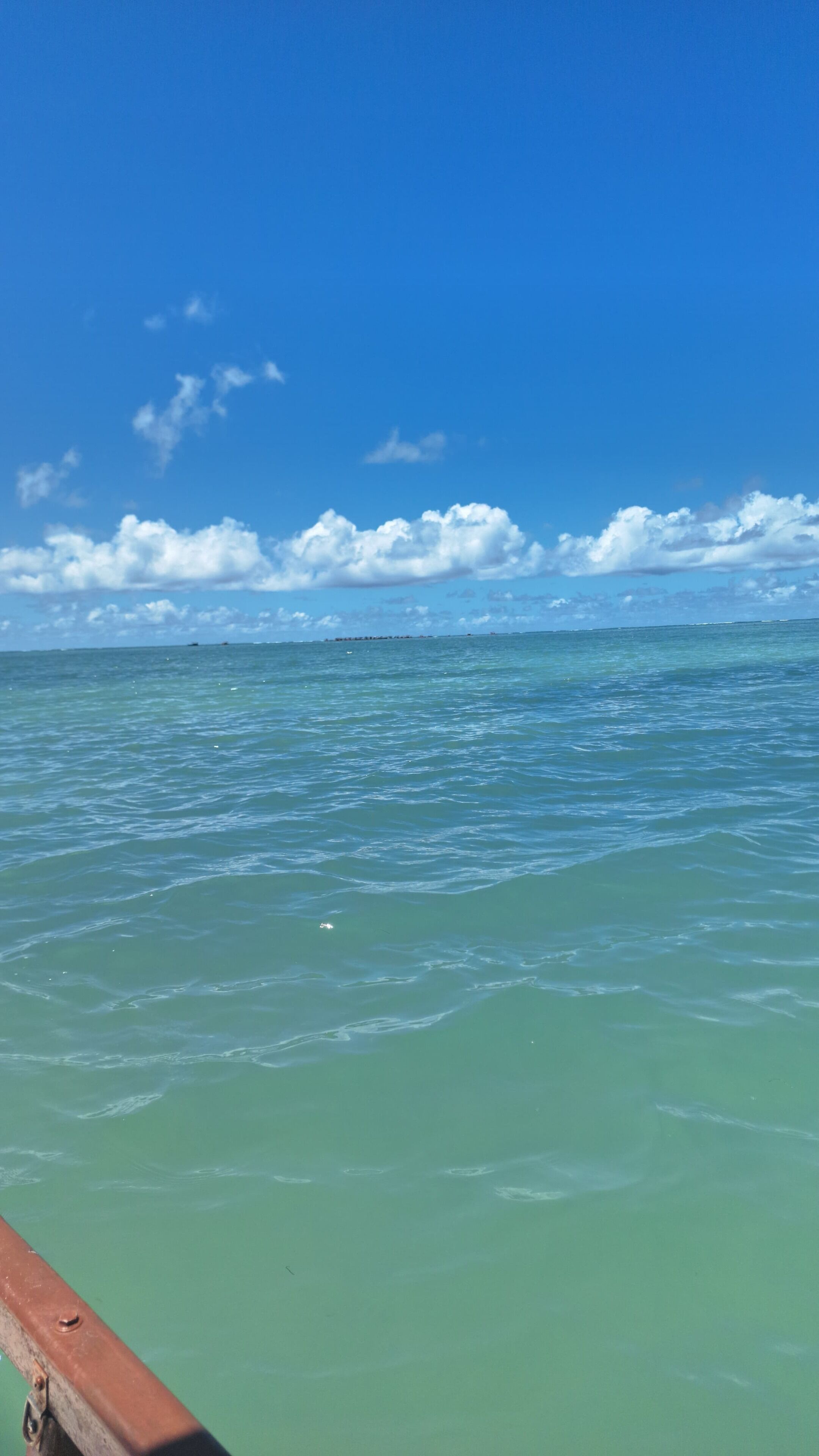 A view of the ocean with a wooden railing in the foreground.