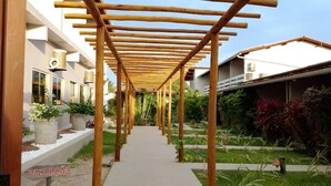 A covered walkway with wooden beams, leading to a building with a reception sign. - Pousada Maresia (São Miguel dos Milagres)