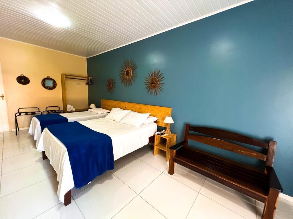 Habitación de hotel con dos camas, un banco de madera y detalles decorativos en la pared.