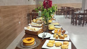 A buffet table with various baked goods and a decorative vase. - Pousada Maresia (São Miguel dos Milagres)