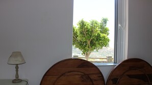 Une chambre à coucher avec deux têtes de lit en bois, une table de chevet avec une lampe et une fenêtre donnant sur un arbre et un paysage.
