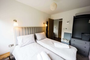 A hotel room with a double bed, bedside lamps, a wardrobe, and a small seating area.