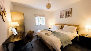 A neatly arranged bedroom with a bed, bedside tables, a desk, and a chair. - Luxury chalet in wonderful Pembrokeshire National Park, beach & coast path (Nolton Haven)