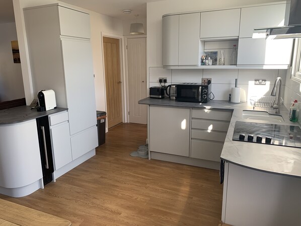 A modern kitchen with white cabinets, a microwave, a toaster, and a sink.