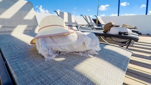 A small white dog with a pink and yellow hat sitting on a lounge chair. - Brand New Two Br Penthouse With a Private Roof Patio! Totally Equipped (Tulum)
