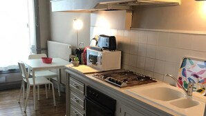 A kitchen with white cabinets, a stove, a sink, and a window. - EGLANTINE  (Dinan)