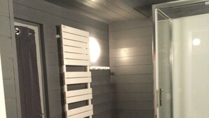 A bathroom with a shower, a towel rack, and a door. - EGLANTINE  (Dinan)