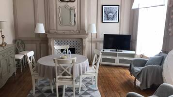 Un salon avec une cheminée, un téléviseur et un coin repas comprenant des chaises et une table.