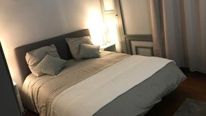 A neatly made bed with a headboard, a bedside lamp, and a nightstand. - EGLANTINE  (Dinan)