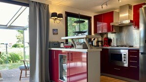 A modern kitchen with red cabinetry, a built-in microwave, and a gas stove. - Holiday Home With Winter Garden by the Lauwersmeer for 4 Guest (Anjum)
