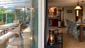 A modern kitchen with red cabinets, stainless steel appliances, and a dining area with wooden furniture and a glass table. - Holiday Home With Winter Garden by the Lauwersmeer for 4 Guest (Anjum)
