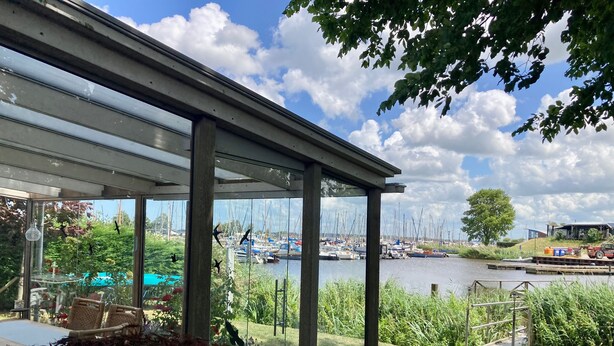 A covered patio with a view of a marina and boats. - Holiday Home With Winter Garden by the Lauwersmeer for 4 Guest (Anjum)