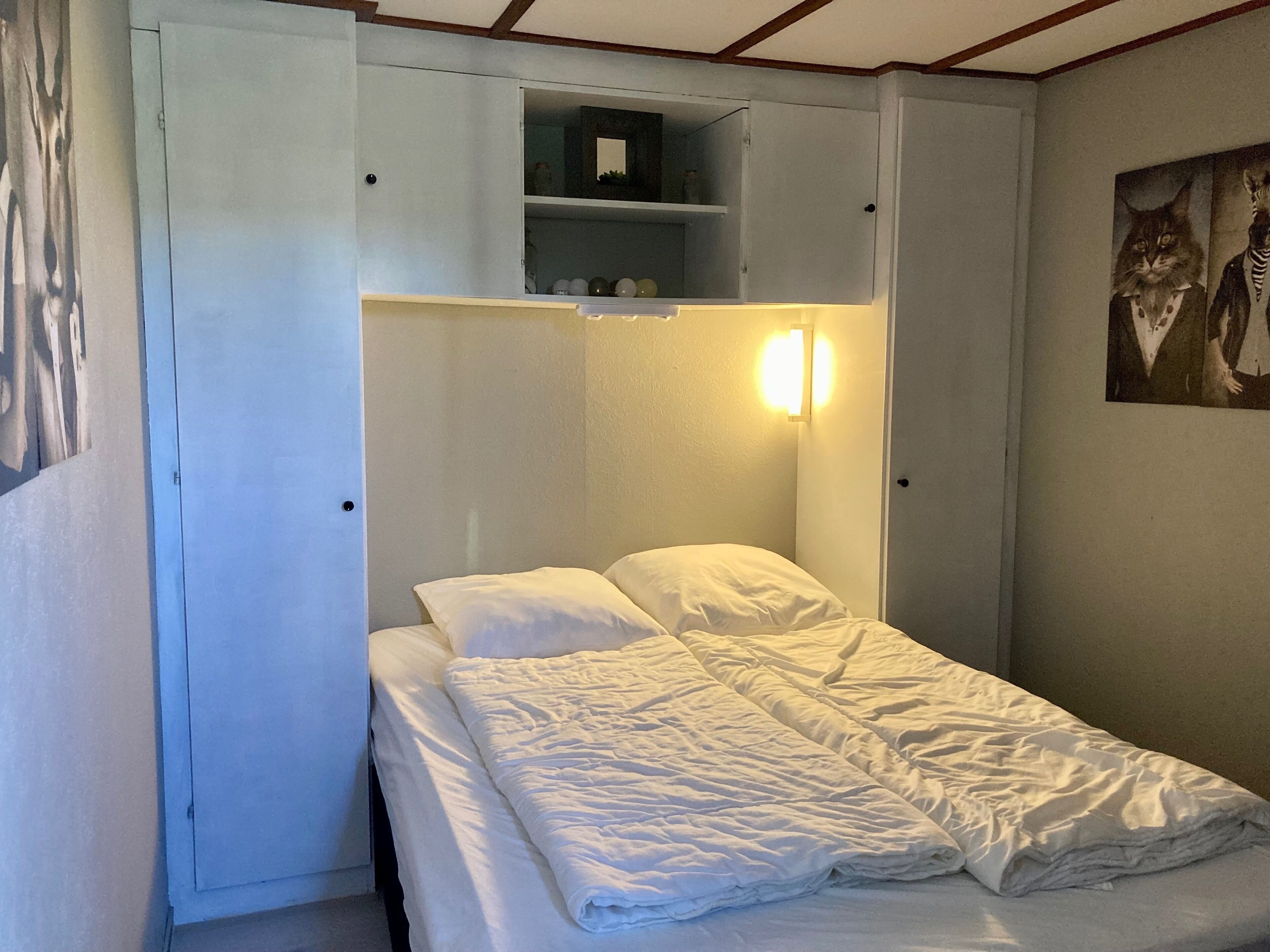 A small, single-bed room with a built-in wardrobe and a wall-mounted shelf.