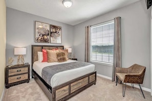 A bedroom with a bed, bedside tables, a chair, and artwork on the wall.