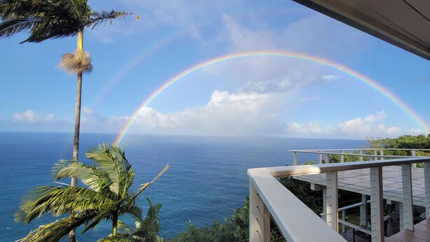 A balcony with a view of the ocean and a rainbow. - Paradise Bluff: Cliffside Home w/Gorgeous Ocean Views and Tropical Garden (Laupahoehoe)