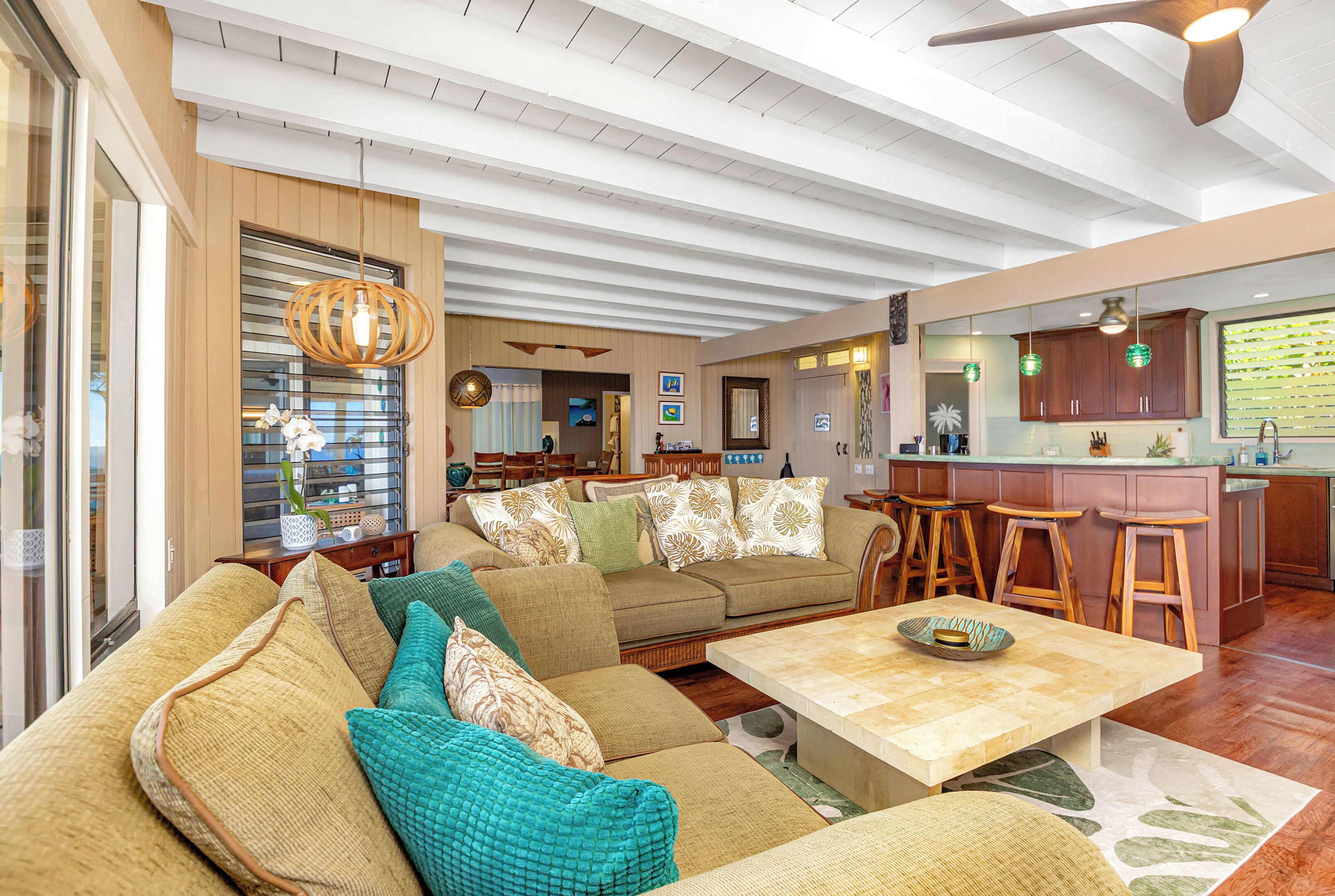 A spacious living area with a large sofa, a coffee table, and a kitchen area with bar stools.